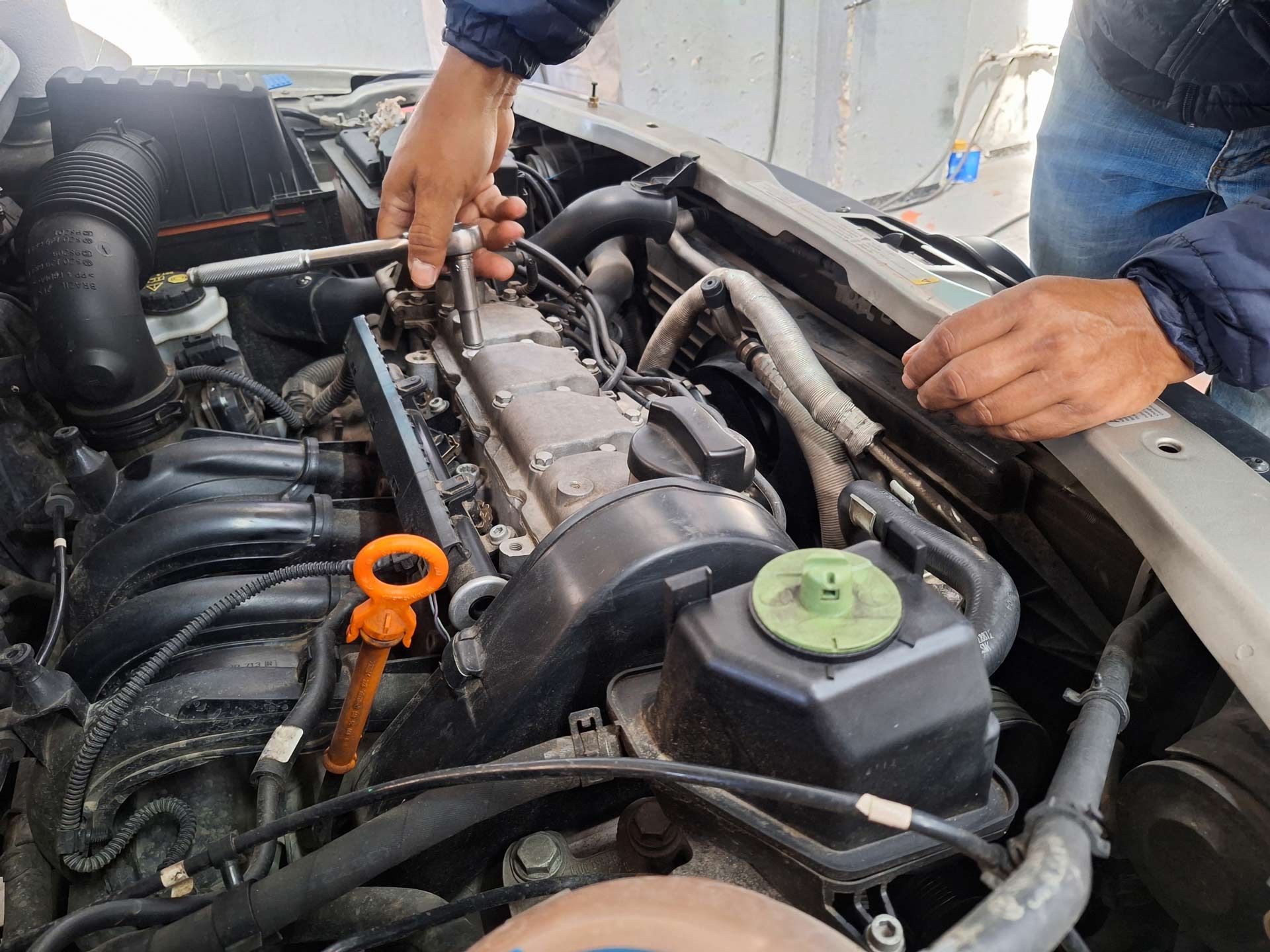 Mechanic performing auto transmission repair under hood with socket wrench and exposed engine parts — Smyrna, GA — All Pro Transmission