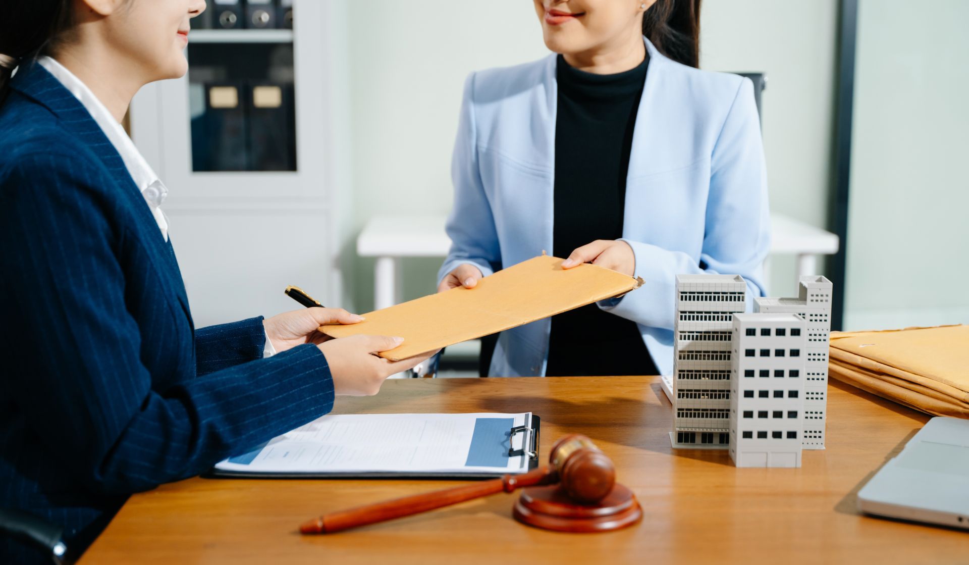 A lawyer is handing an envelope to her client.