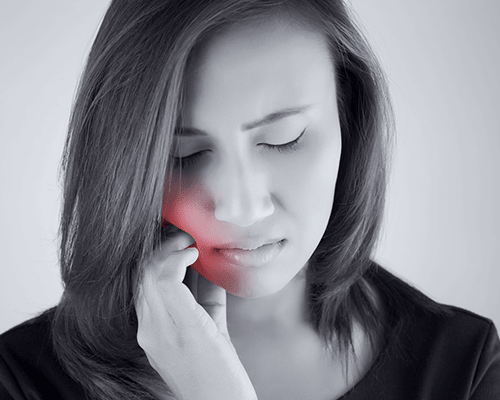 A woman is holding her face in pain because of a toothache.