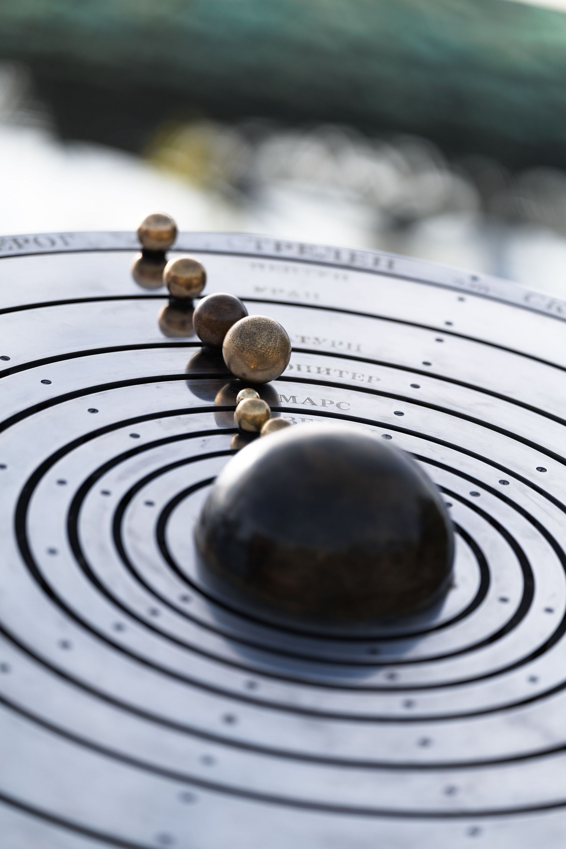 Model solar system with planets arranged on concentric rings, featuring a large black sphere in front.