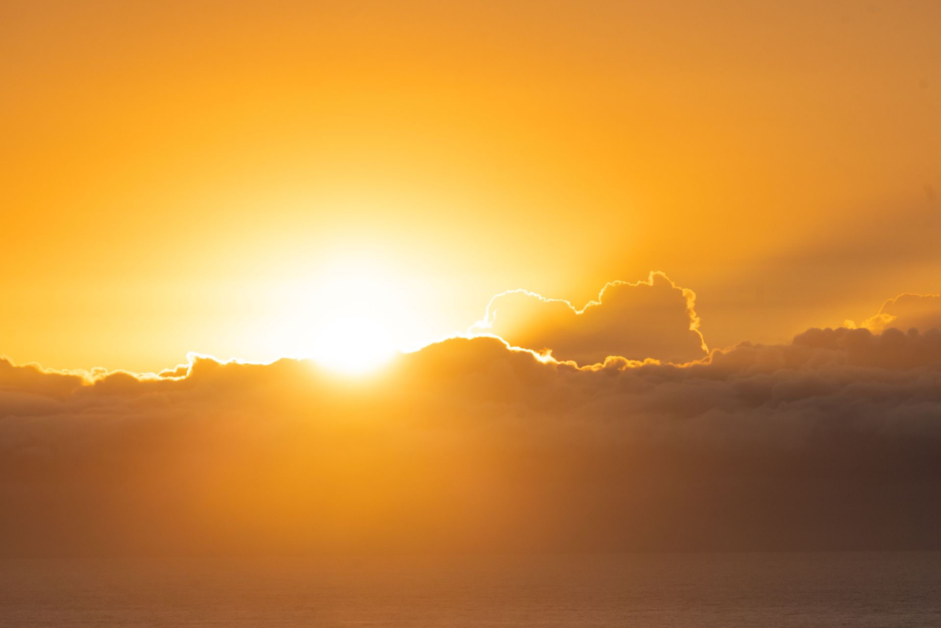 Golden sunset over a cloudy horizon with warm orange sky and bright sunlight