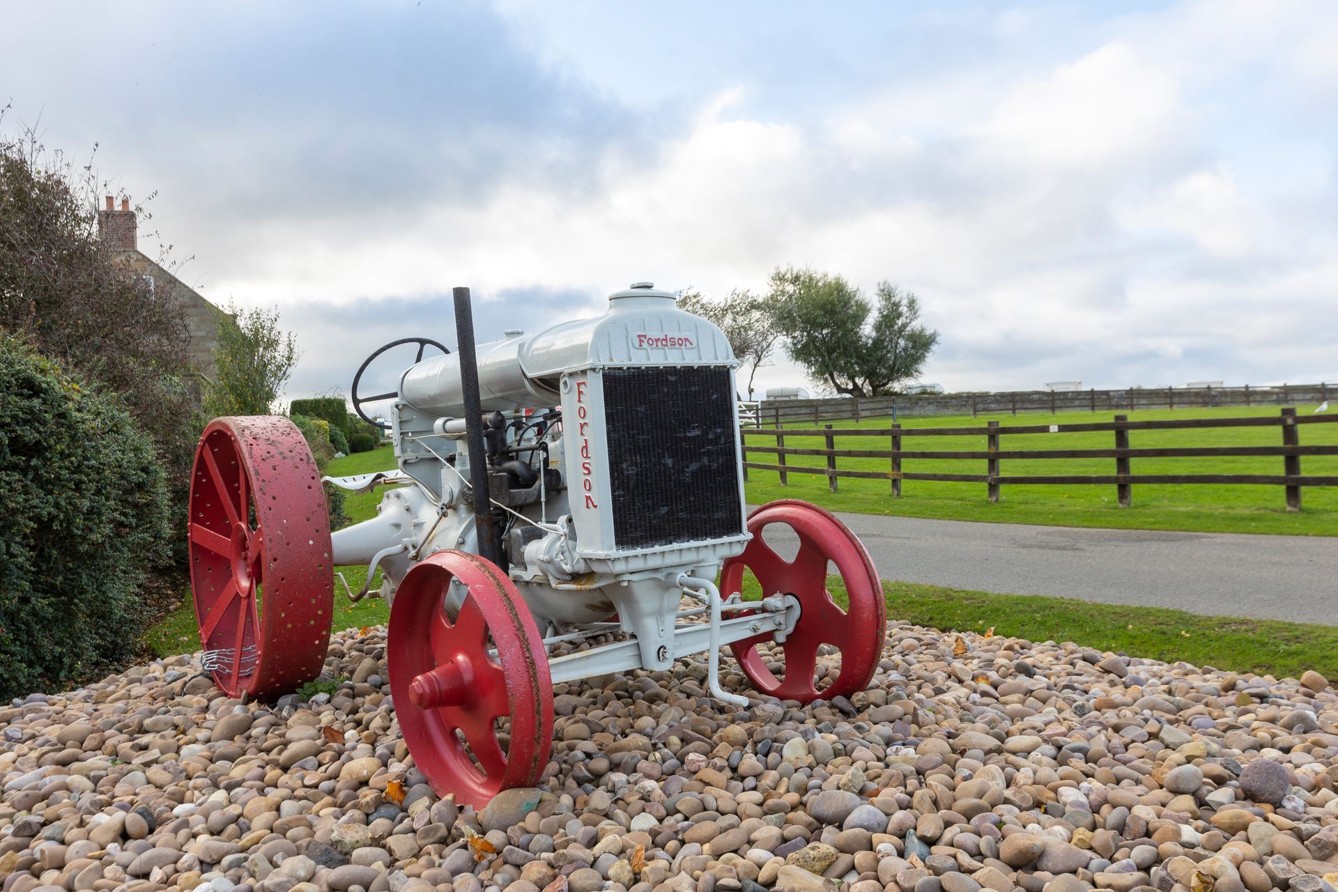 A white tractor with red wheels is sitting on a pile of rocks.