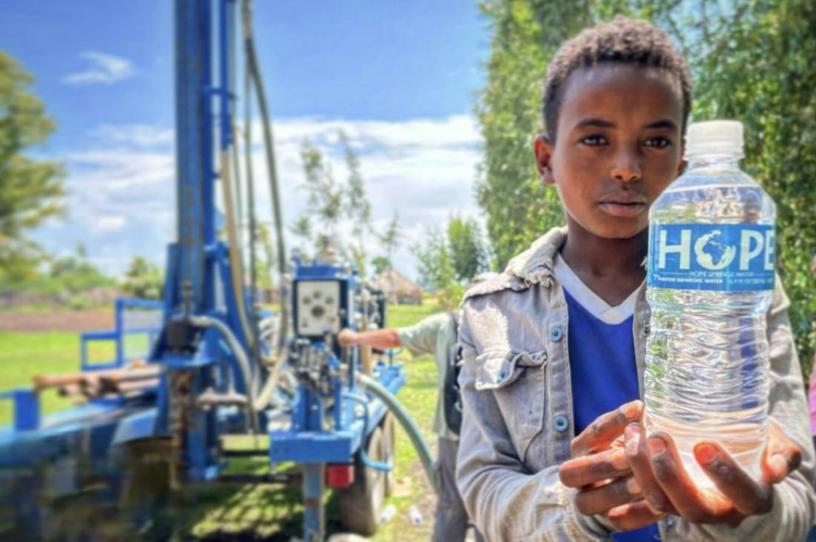 A young boy is holding a bottle of water in his hands.