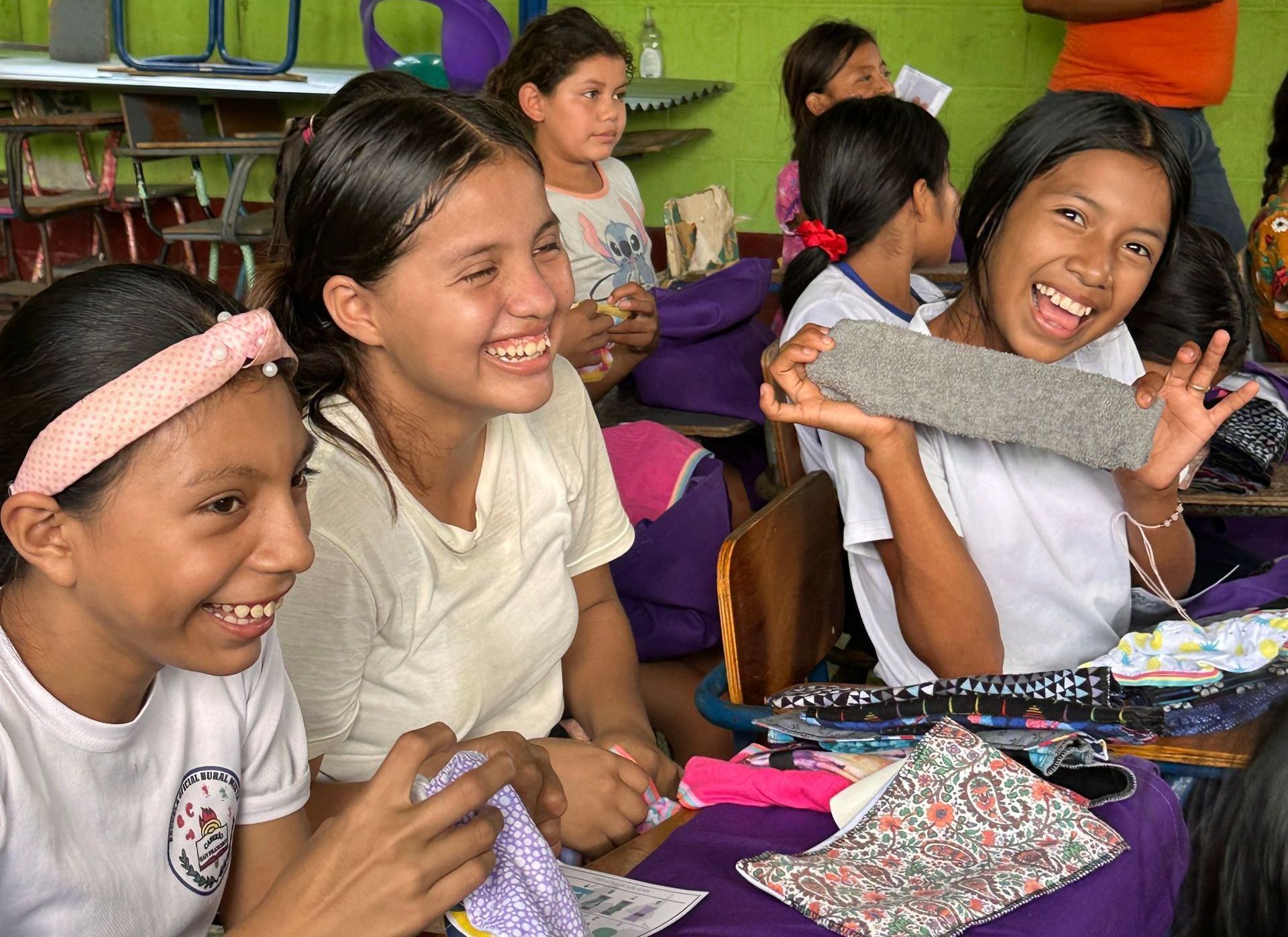 A group of young girls are sitting at desks in a classroom.