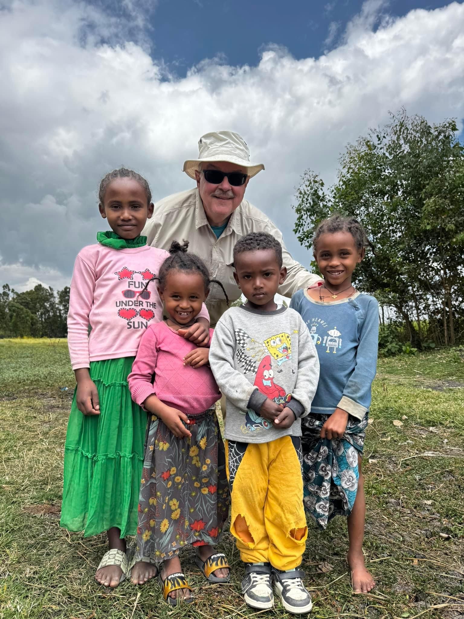 A man and three children are posing for a picture in a field.