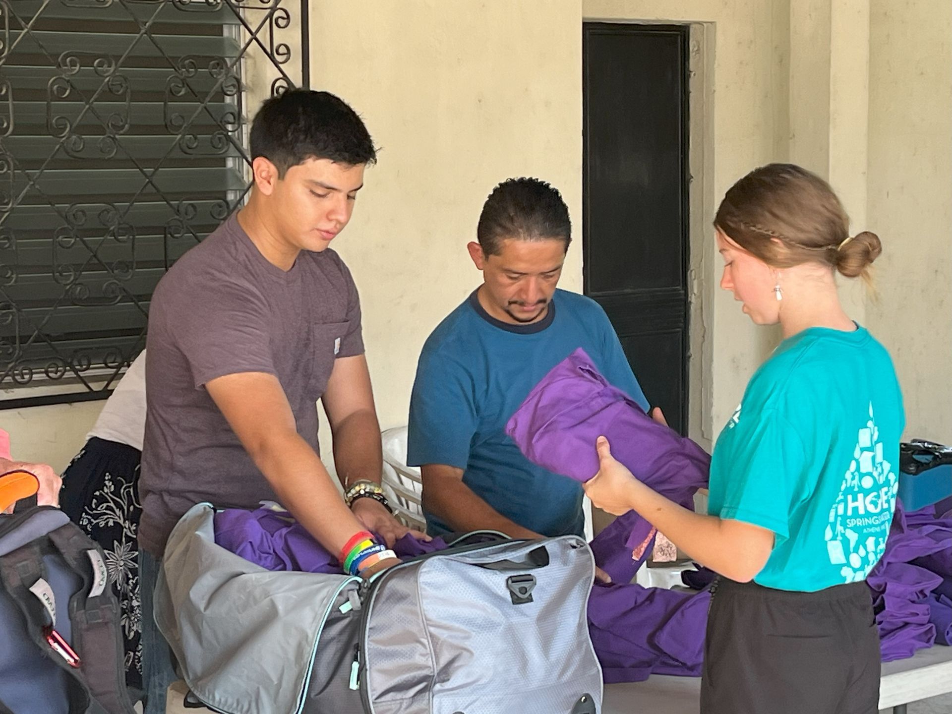 A woman in a green shirt is talking to two men