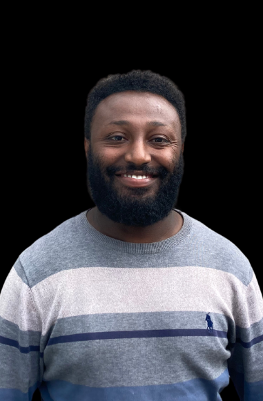 A man with a beard is wearing a striped sweater and smiling.