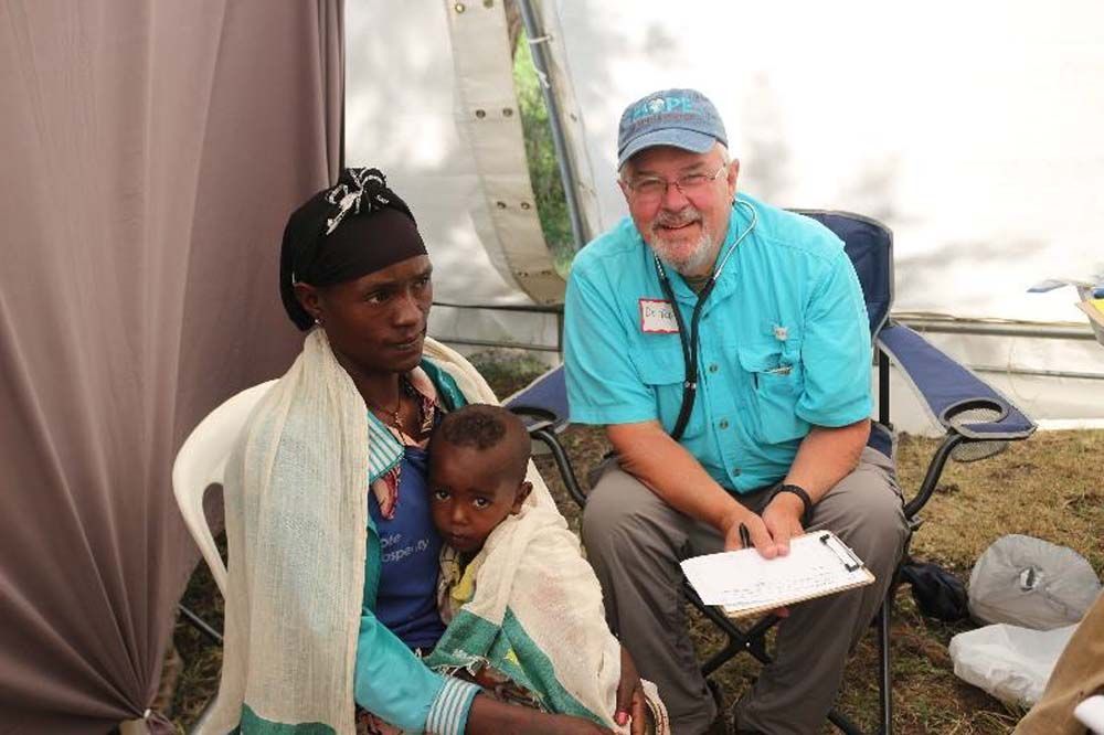 A man is sitting next to a woman holding a baby.