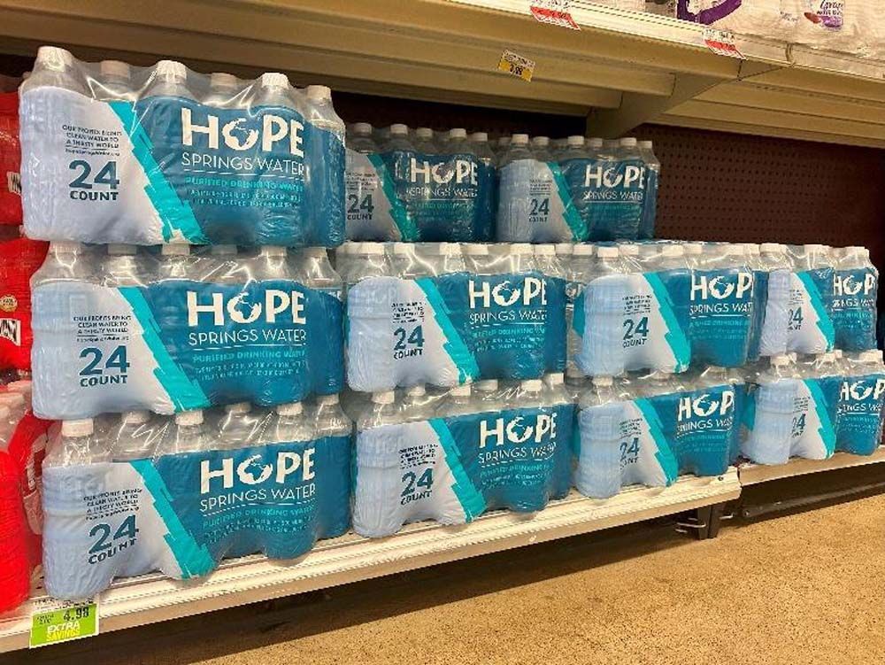 A shelf filled with lots of bottles of hope water.