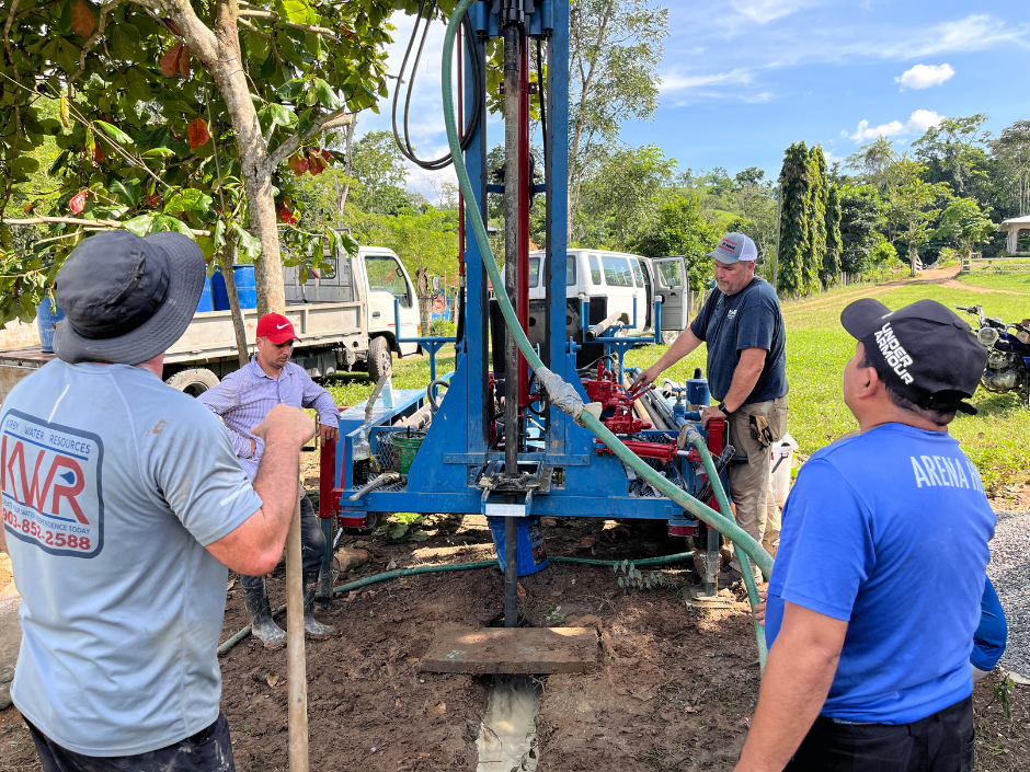 A group of men are working on a machine in a field.