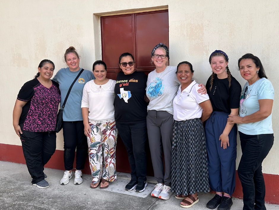 A group of women are posing for a picture in front of a building.