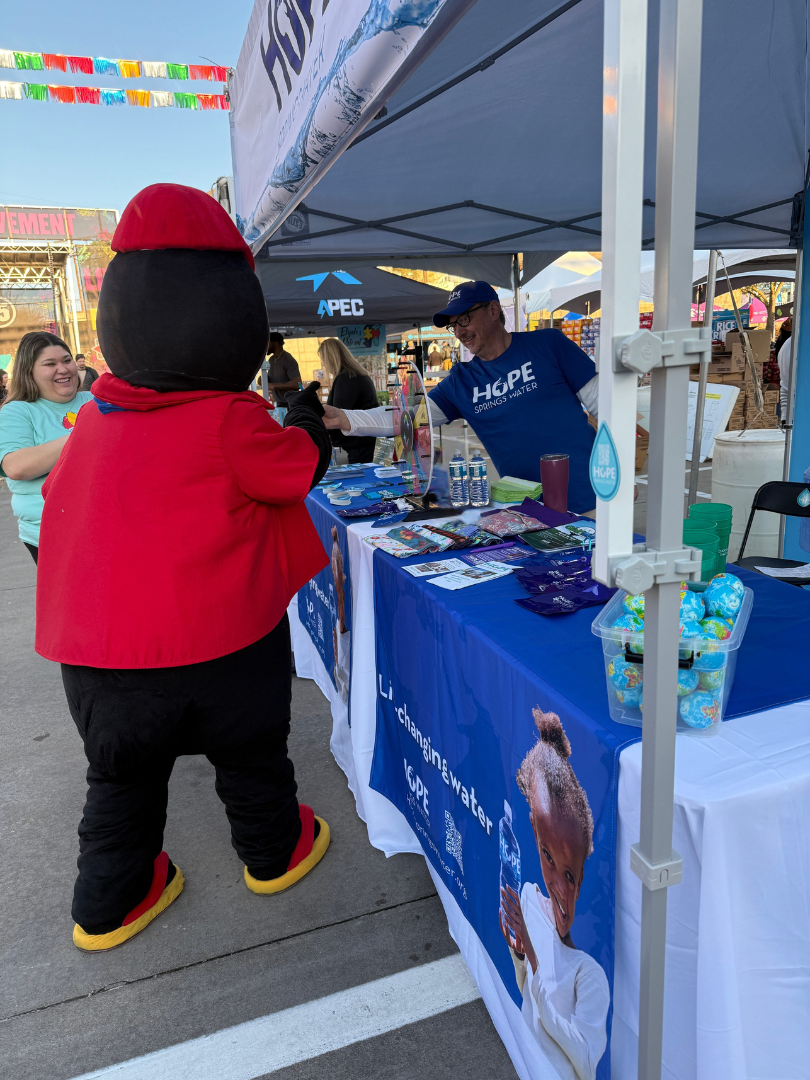 A mascot is standing in front of a table with an ice cream cone on it.