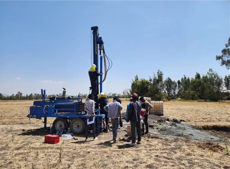 A group of people standing around a machine in a field