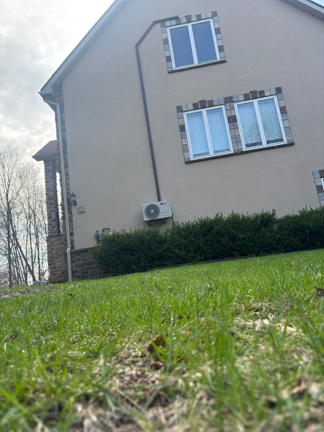 Low-angle view of a beige house with white windows and a green lawn in front