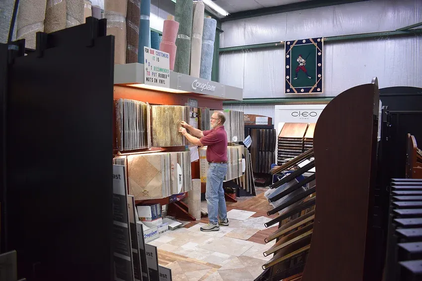 A man is standing in a store looking at tiles.