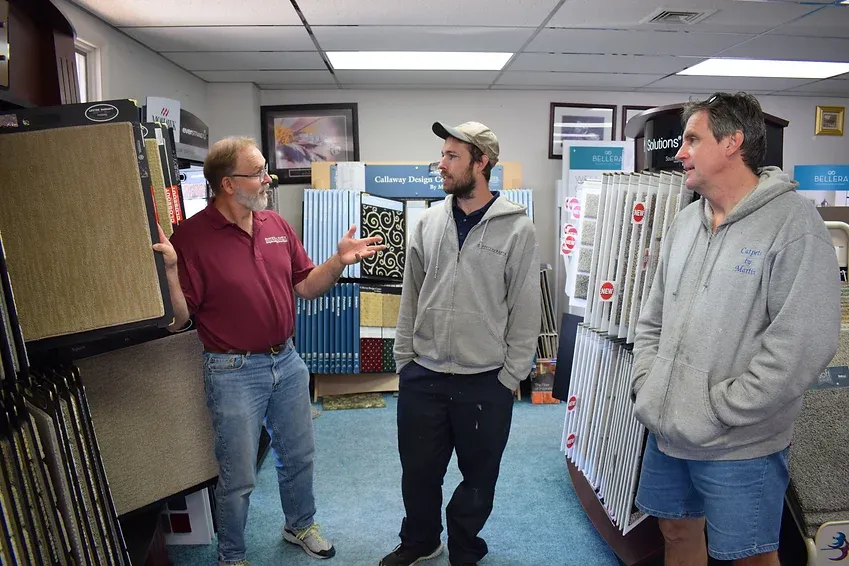 Three men are standing in a room talking to each other.