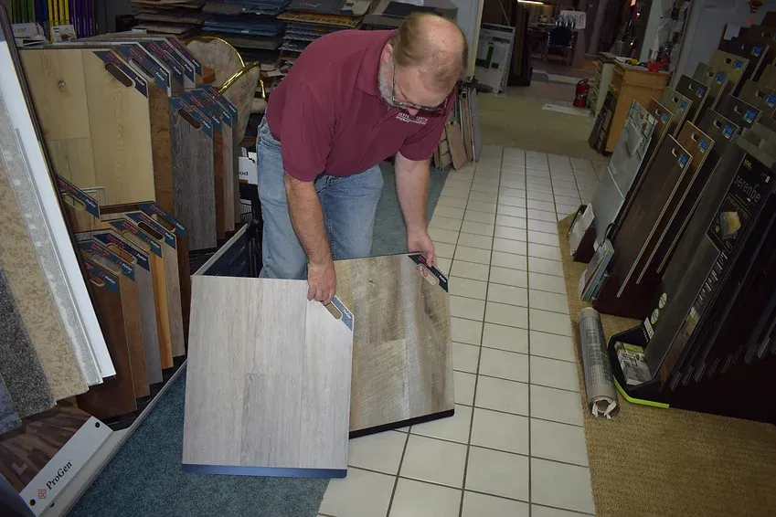 A man in a red shirt is holding a piece of wood