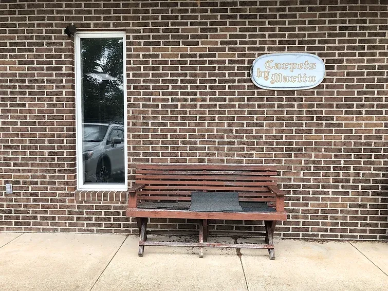 A wooden bench is sitting in front of a brick building.