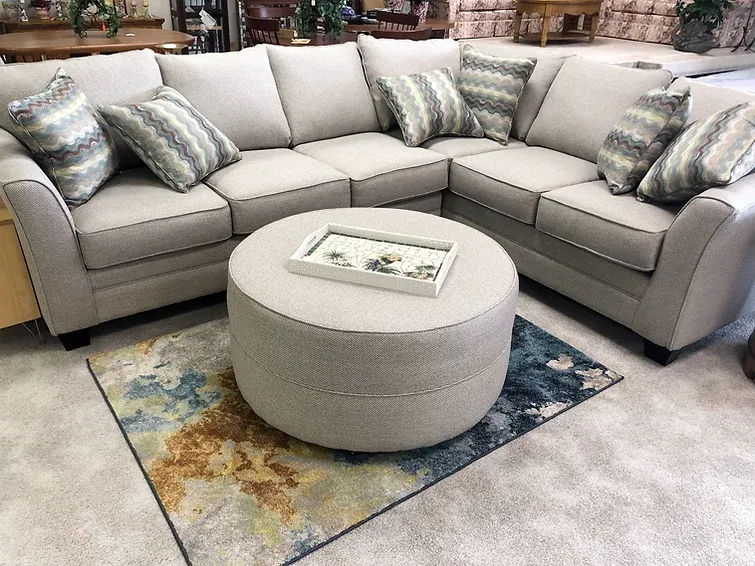 A living room with a sectional couch and a round coffee table.