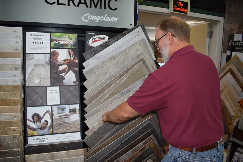 A man is holding a stack of tiles in a store.