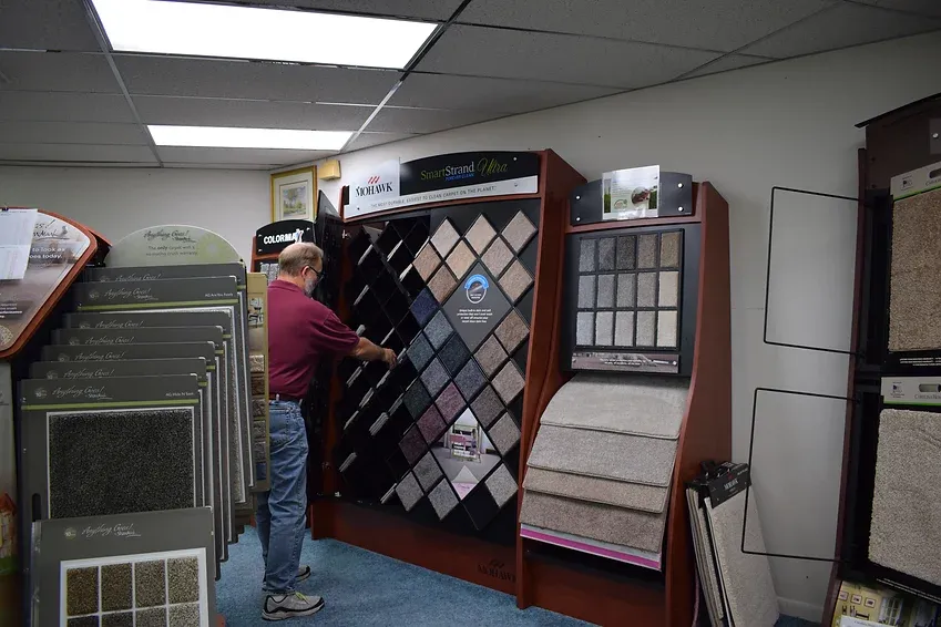 A man is looking at carpet samples in a store.