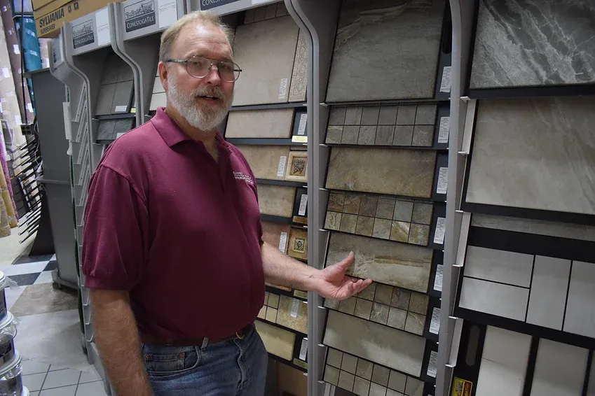 A man is standing in front of a display of tiles in a store.