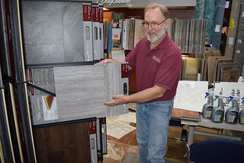 A man in a red shirt is holding a tile in a store.