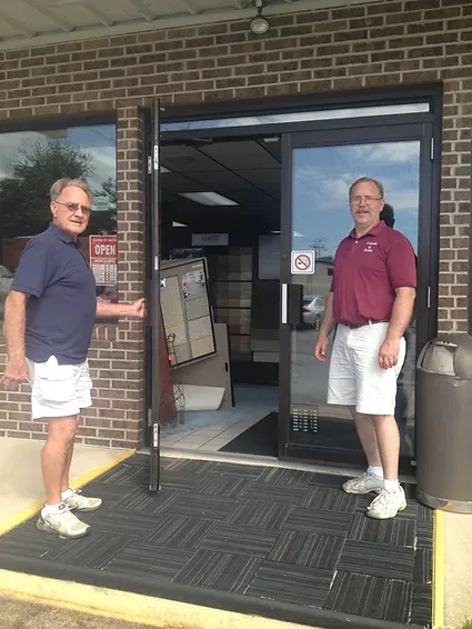 Two men are standing in front of a brick building