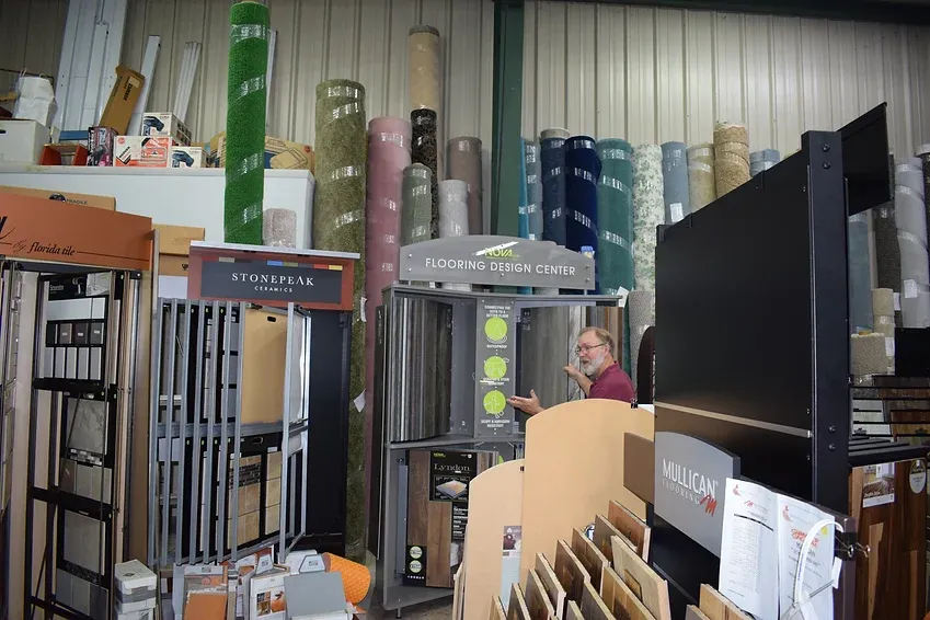 A man is standing in a store looking at a display of carpets