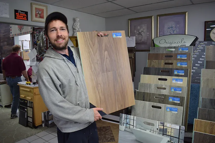 A man is holding a piece of wood in a store