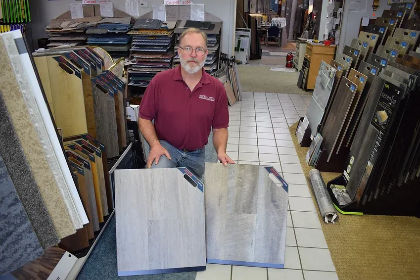 A man in a red shirt is holding two pieces of wood