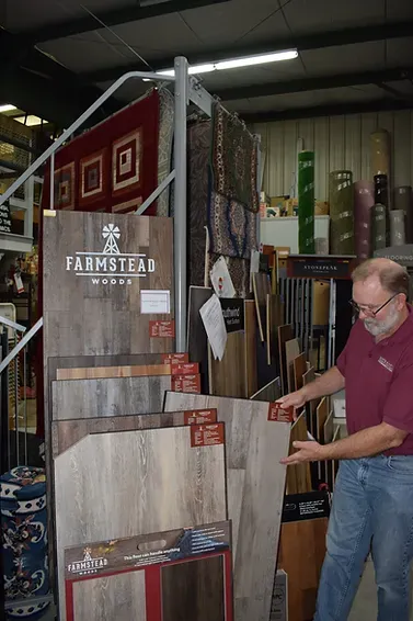 A man is standing in front of a display of flooring in a store.