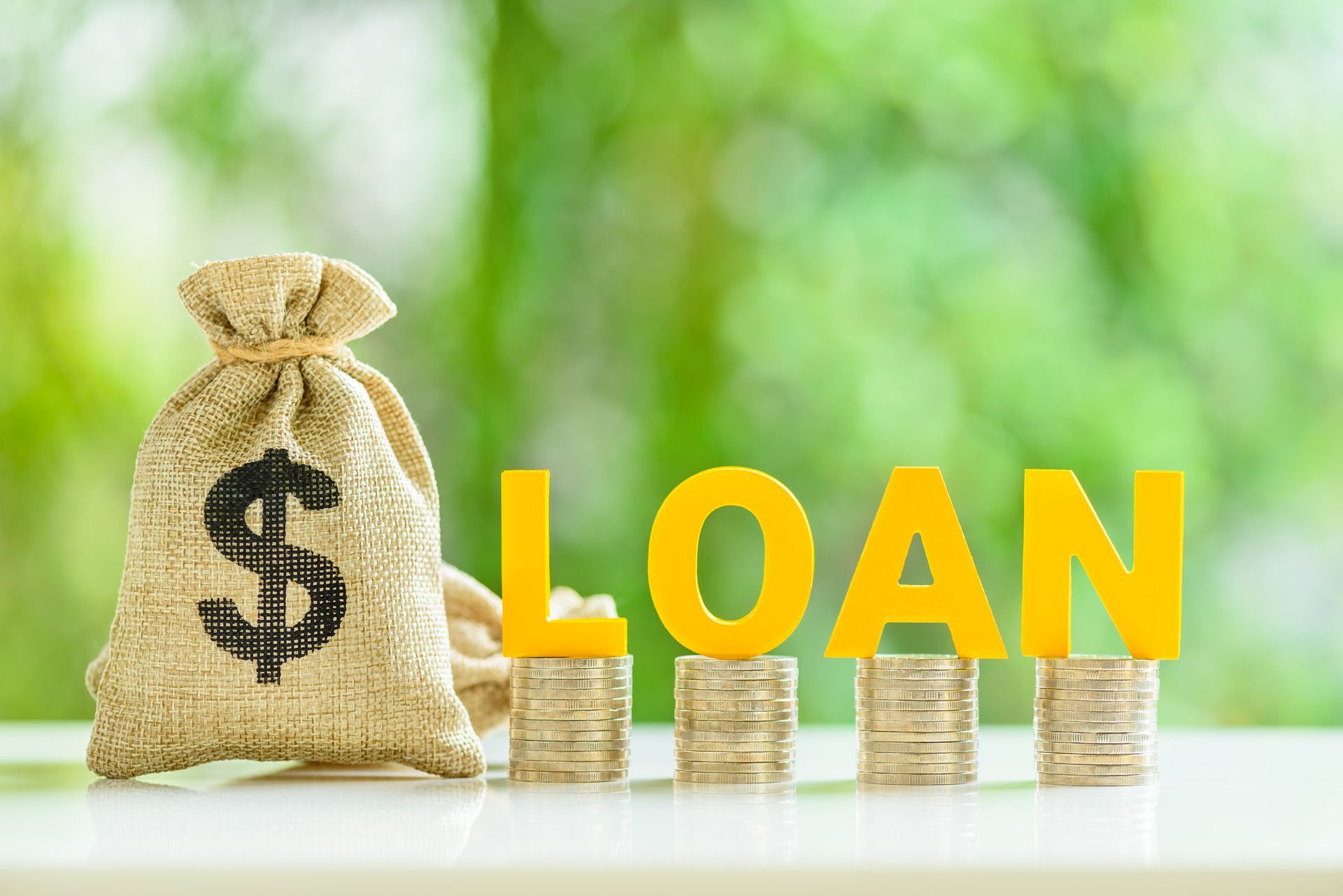 Money bag and stacked coins beside yellow “LOAN” text on a bright green background