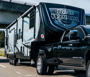 A black truck is towing a road warrior trailer