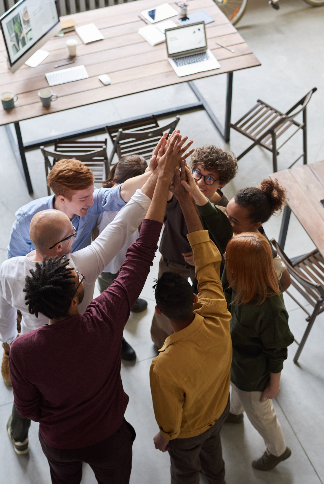 A group of people are giving each other a high five in an office.