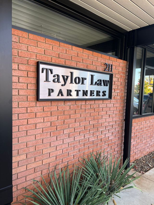 Taylor Law Partners sign on red brick exterior wall beside a doorway