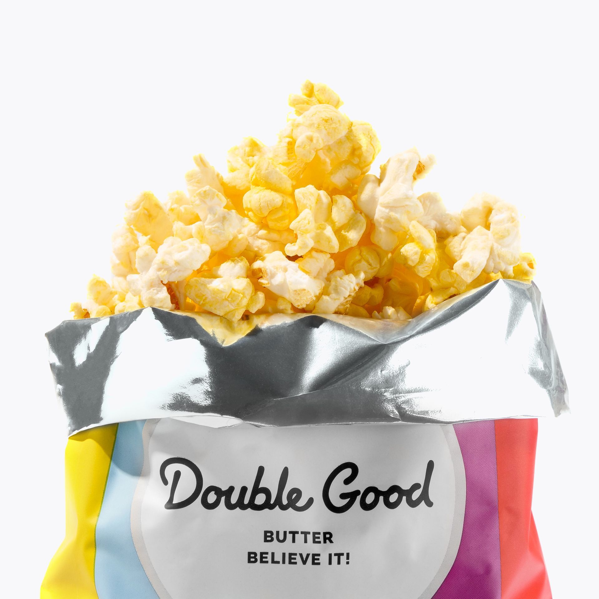 Butter popcorn spilling from a Double Good bag; bag has colorful edges, white center with text.