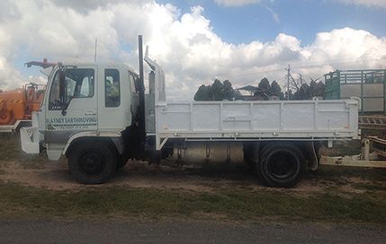 A white dump truck is parked on the side of the road.