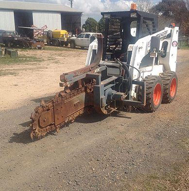 A bobcat is parked on the side of the road