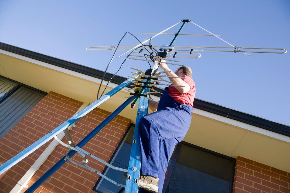 A Man is Sitting on a Ladder Working on an Antenna — Hendo's TV Antennas & Installations in White Rock, QLD