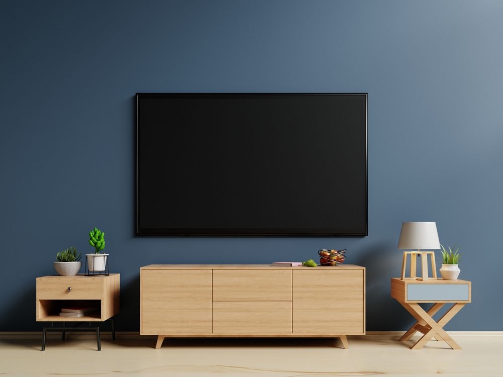 A Flat Screen Tv is Hanging on a Blue Wall Above a Wooden Entertainment Center — Hendo's TV Antennas & Installations in Trinity Beach, QLD