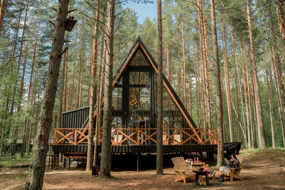A-frame cabin in a pine forest with a wooden deck and picnic table in front