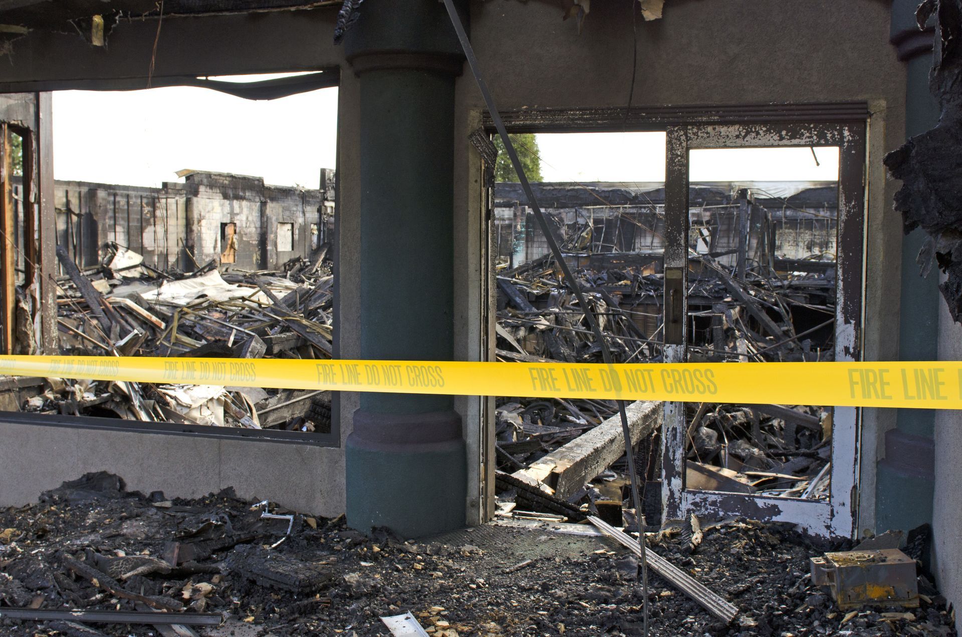 Burned-out building interior with yellow caution tape across the debris-strewn ruins.