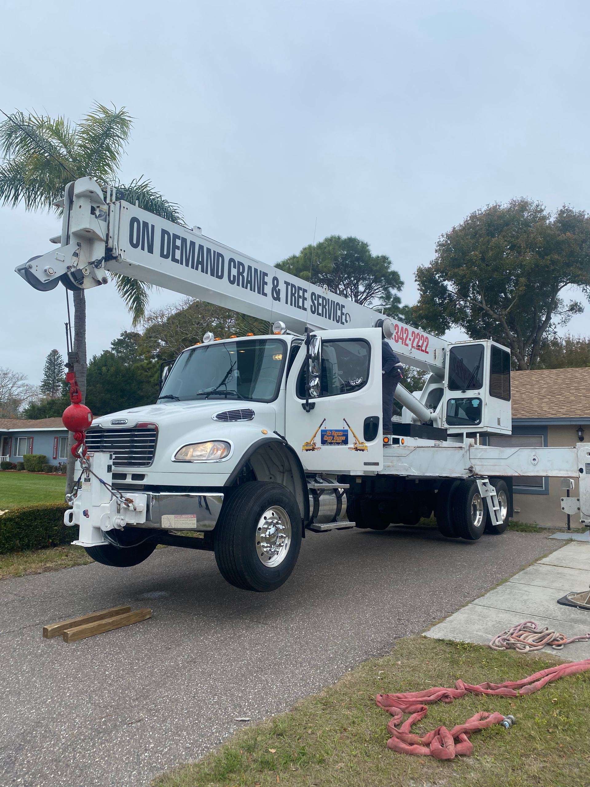 White crane truck with extended arm in a residential area.