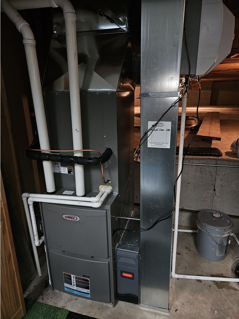 Furnace and ductwork in a basement setting. Gray metal with white pipes.