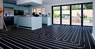 Black radiant floor heating system installed in a modern kitchen with white cabinets and large windows.