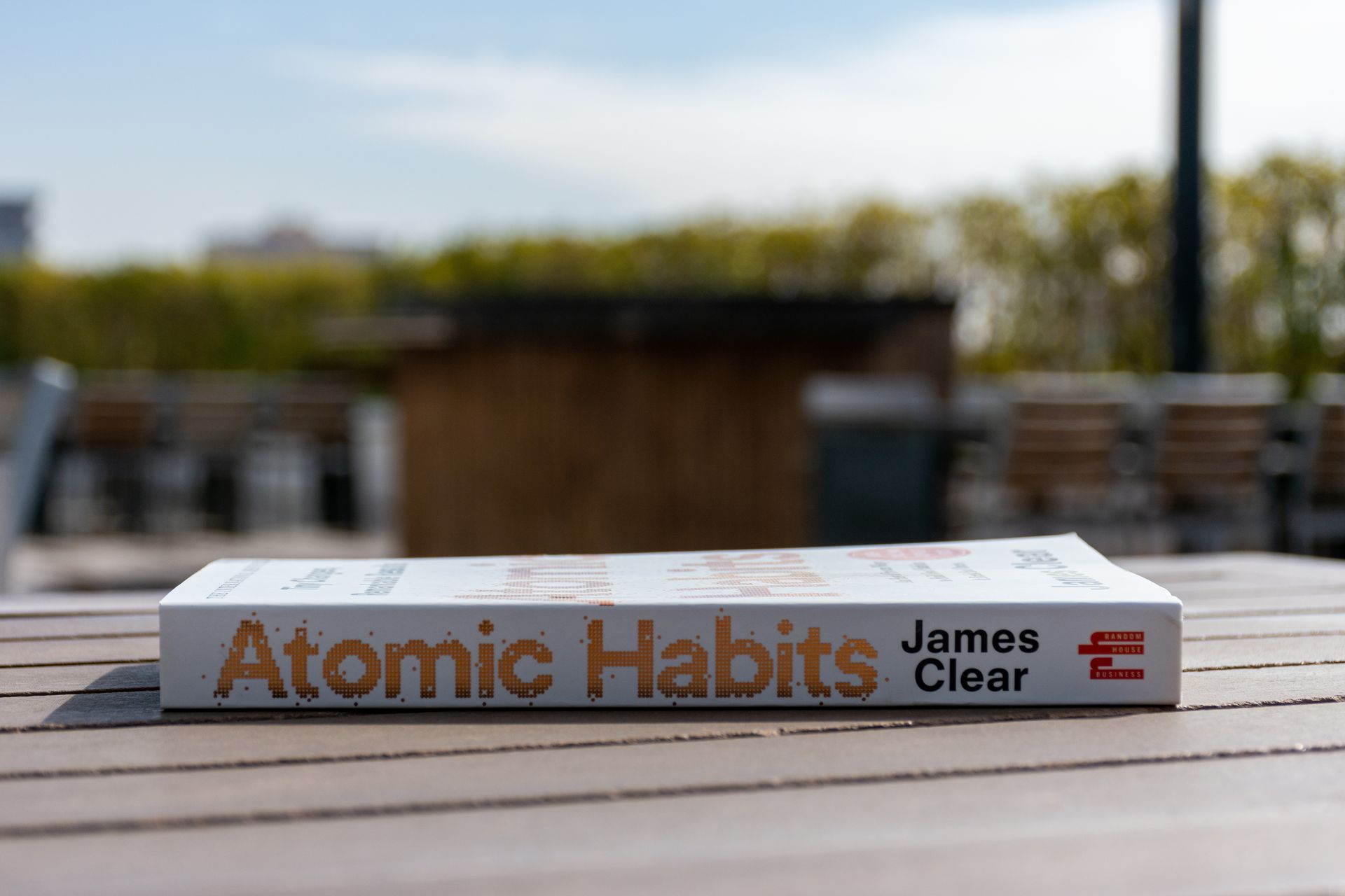 A book called atomic habits by james clear is sitting on a wooden table.