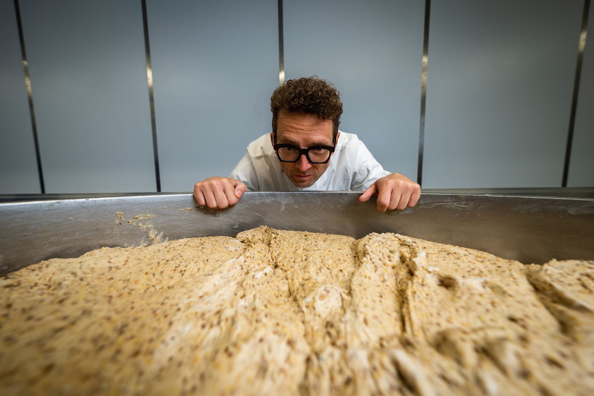 A man is looking at a large pile of dough.
