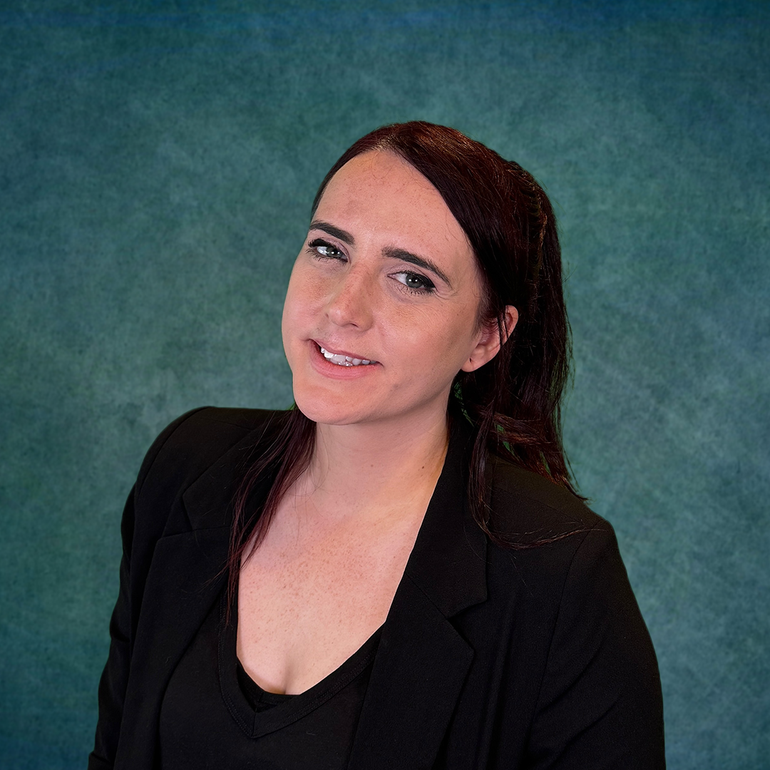 A woman in a black shirt is standing in front of a blue background.