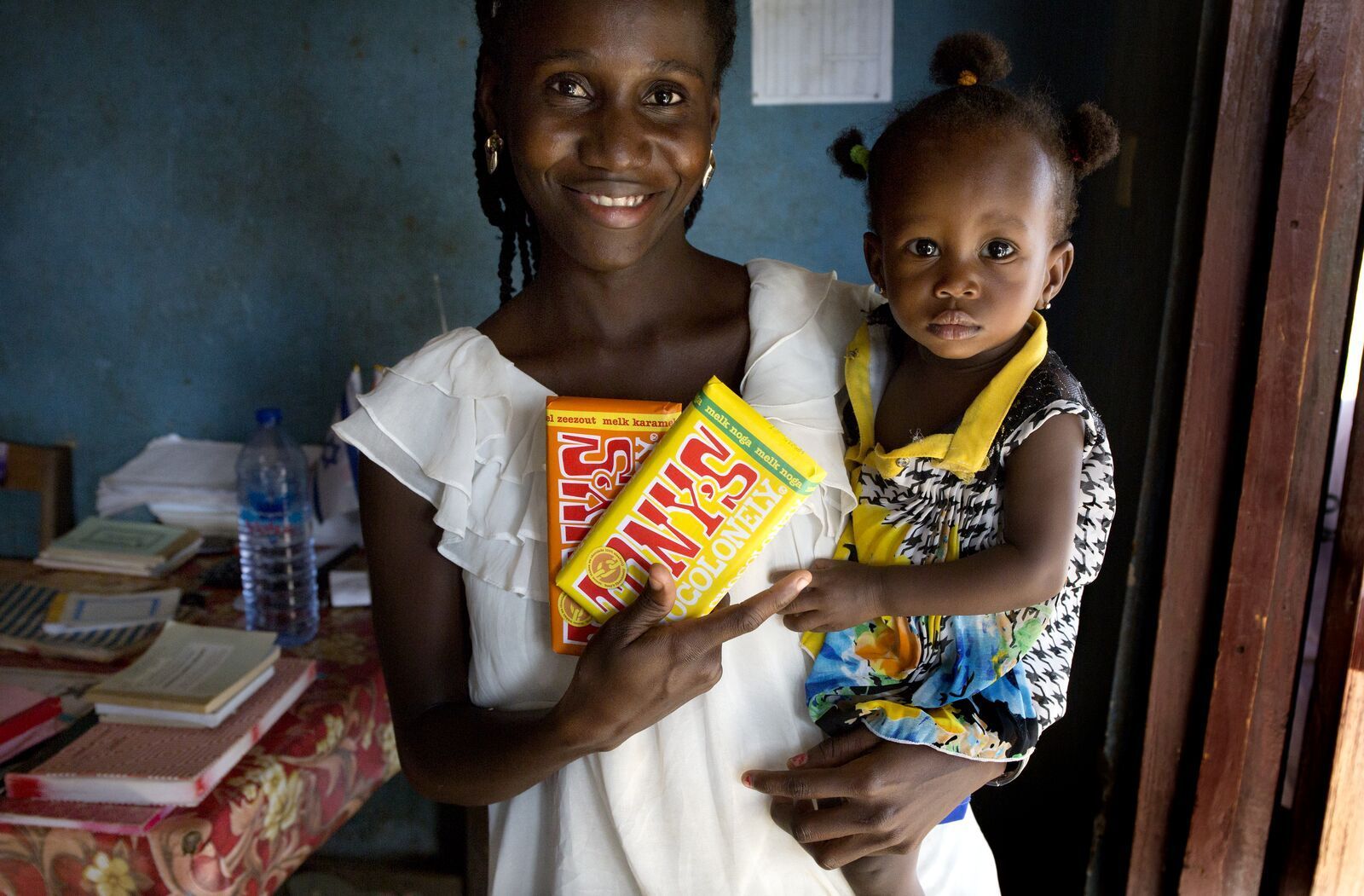 A woman is holding a child and a packet of stanley candy